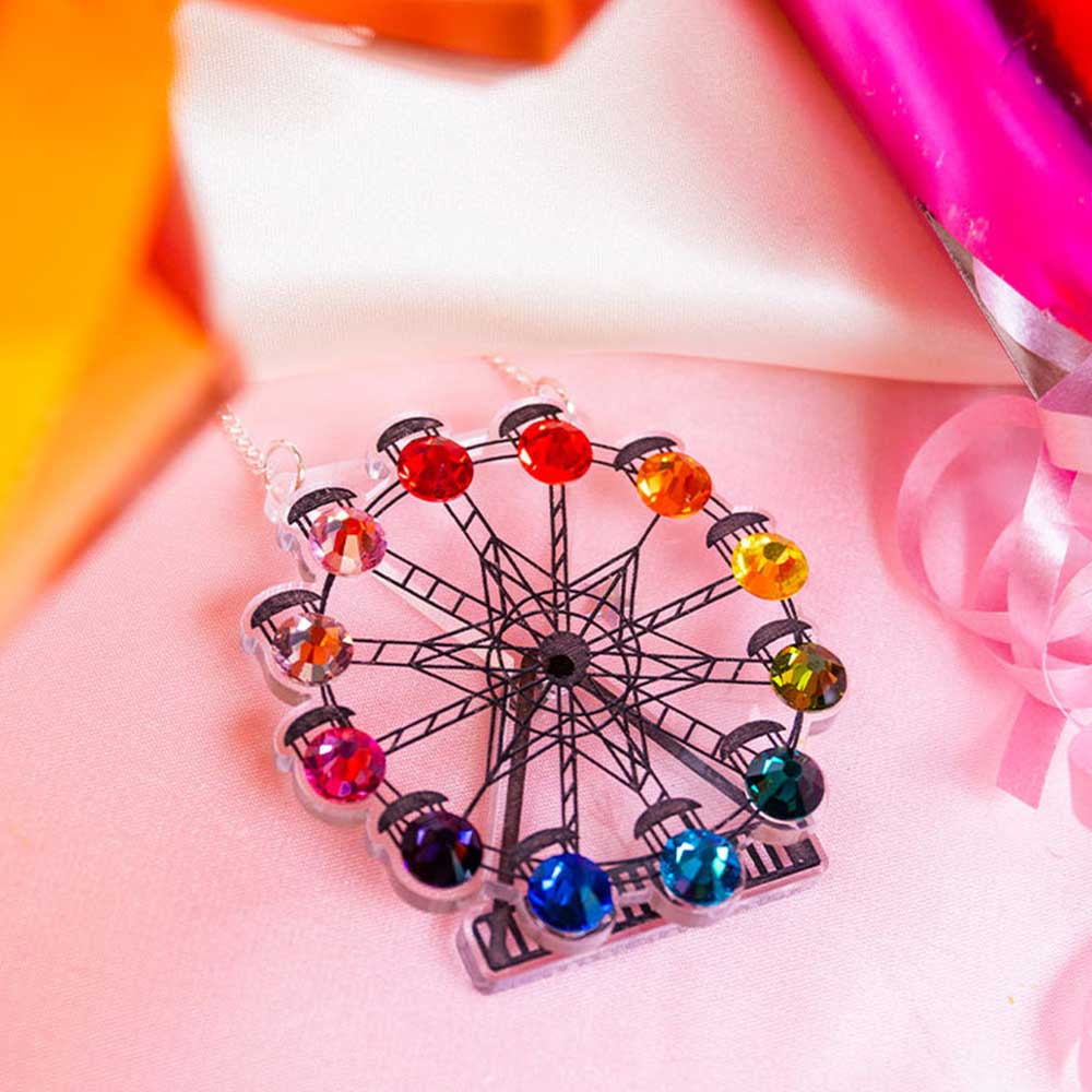 Ferris wheel necklace against pink balloons and ribbon