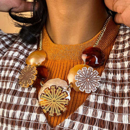 Seed pods necklace worn over an orange jumper