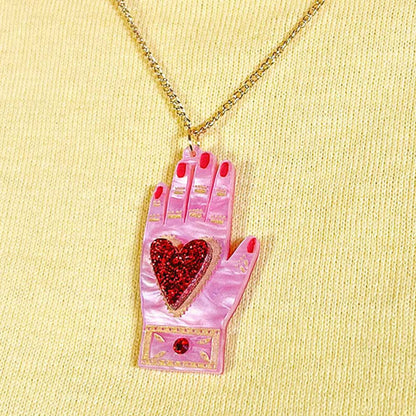 Heart in hand pendant worn on a yellow knit