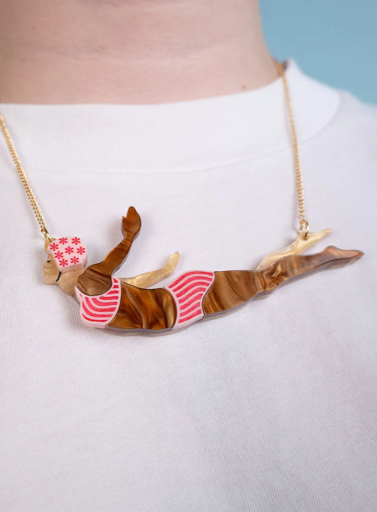 Wild swimmer necklace worn over a white top