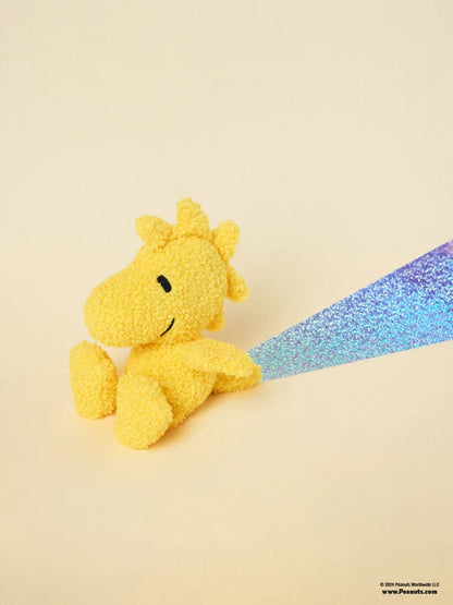 Woodstock teddy sitting in front of a rainbow glitter streak