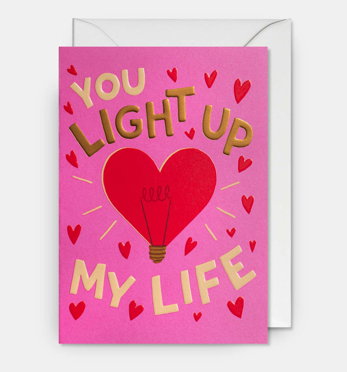 Lagom card: a red heart-shaped light bulb on pink, with gold 'You light up my life'